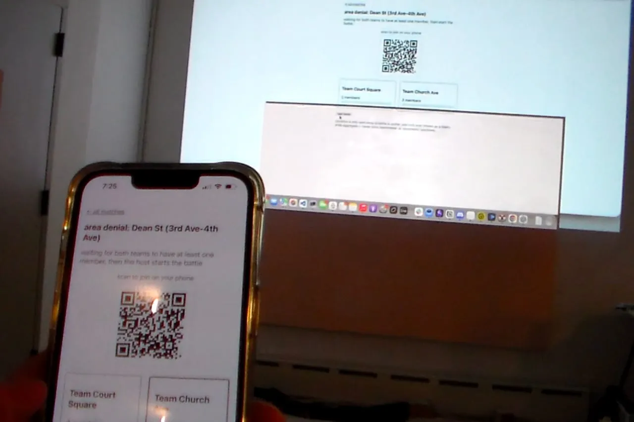 A phone and projector displaying QR codes during a demo.